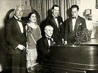 George Gershwin (Standing far right) At the piano, the French composer Maurice Ravel.